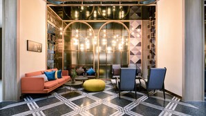Eine moderne Lounge mit einer Couch, Sesseln, einem Couchtisch und einem gemusterten Boden.