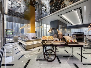 A modern cafe with a marble floor, a buffet counter, and a coffee machine.