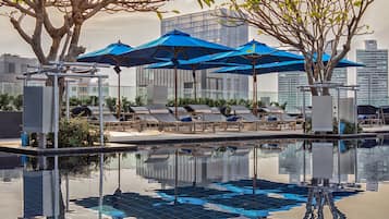 Una piscina al aire libre, sombrillas, sillones reclinables de piscina