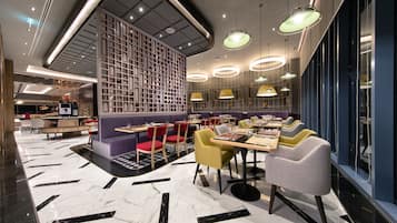 A modern restaurant with marble flooring, multiple dining tables, and chairs.