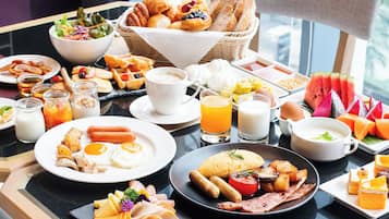 A breakfast buffet with various dishes, including eggs, sausages, and pastries.
