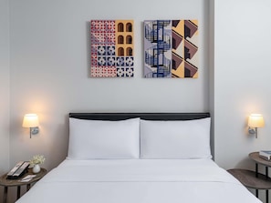 A hotel room with a bed, two bedside tables, a wall-mounted lamp, and two pieces of wall art. - Ibis Bangkok Sukhumvit 24 (Bangkok)
