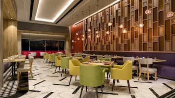 A modern restaurant with a variety of seating options, including tables and booths, and a decorative wall with hanging lights.