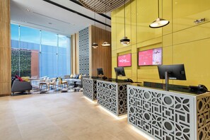 Un área de recepción con diseño moderno, que incluye mostrador de recepción, zona de estar y ventanas amplias.