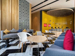 Un vestíbulo moderno con un sofá, sillas, una mesa de recepción y una pared decorativa.