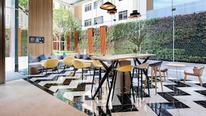 A modern interior with a checkered floor, seating area, and a view of greenery outside. - Ibis Bangkok Sukhumvit 24 (Bangkok)