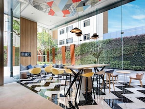A modern interior with a checkered floor, seating area, and a view of greenery outside. - Ibis Bangkok Sukhumvit 24 (Bangkok)