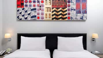 A hotel room with a large abstract painting above the bed, two bedside lamps, and a telephone on the nightstand.