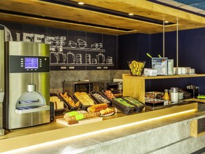 A coffee station with a coffee machine, a toaster, and a variety of baked goods.