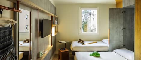 Habitación de hotel moderna con un ventanal grande, televisión de pantalla plana, un banco de madera y una cama con un bolso verde.