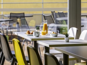 A table with breakfast items, a glass of orange juice, and a potted plant. - ibis budget Montpellier Nord (Montpellier)