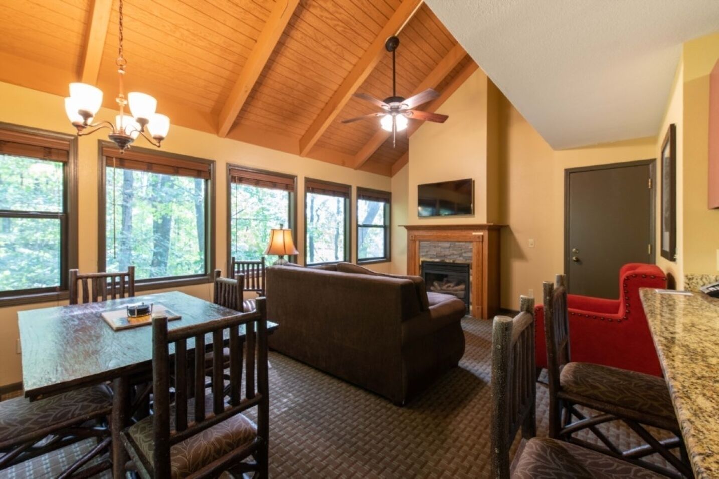 A cozy room with a dining table, chairs, a sofa, a fireplace, and a ceiling fan.