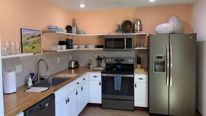 A modern kitchen with white cabinets, stainless steel appliances, and a wooden countertop.