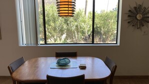 A dining area with a large window, a wooden table, and four chairs.