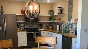 Une cuisine moderne avec une table ronde en bois, un four encastré et un luminaire suspendu.