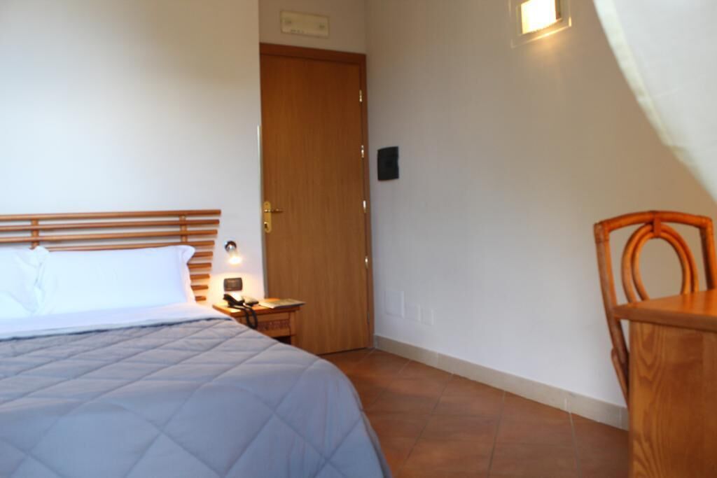 Ein Schlafzimmer mit einem Bett, einem Nachttisch, einem Holzstuhl und einer Tür.