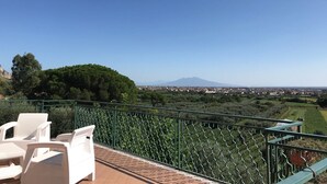 A terrace with white wicker furniture and a view of a mountain and cityscape. - Tenuta Re Ferdinando (Santa Maria Capua Vetere)