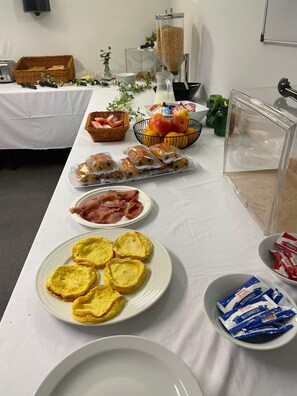 A buffet table with various food items including pastries, fruits, and condiments.