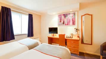 A hotel room with two beds, a desk with a computer, a chair, a desk lamp, a telephone, and a painting on the wall.