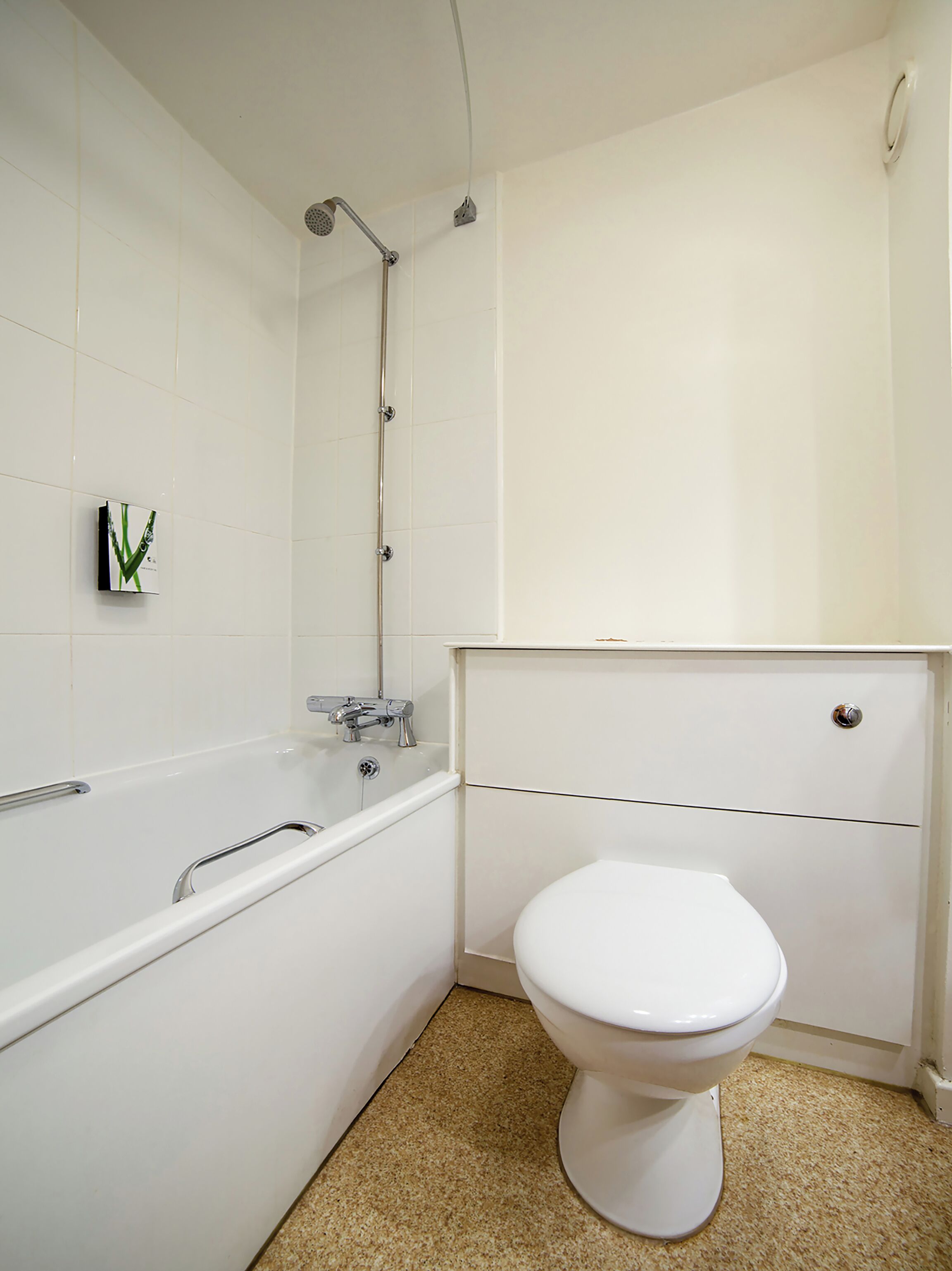 Un baño con una bañera blanca, un inodoro y un cabezal de ducha.