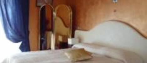 A hotel room with a bed, a nightstand, a mirror, and a window with curtains.