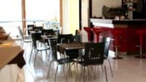 A modern dining area with a bar, large windows, and a view of the sea. - Tea Palace Hotel (Casapulla)