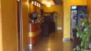 A hotel entrance with a reception desk, a plant, and a sign reading "TEA HOTEL". - Tea Palace Hotel (Casapulla)