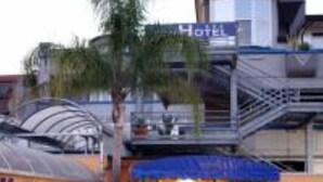 A hotel entrance with a covered walkway, a sign for a tea room, and a palm tree. - Tea Palace Hotel (Casapulla)