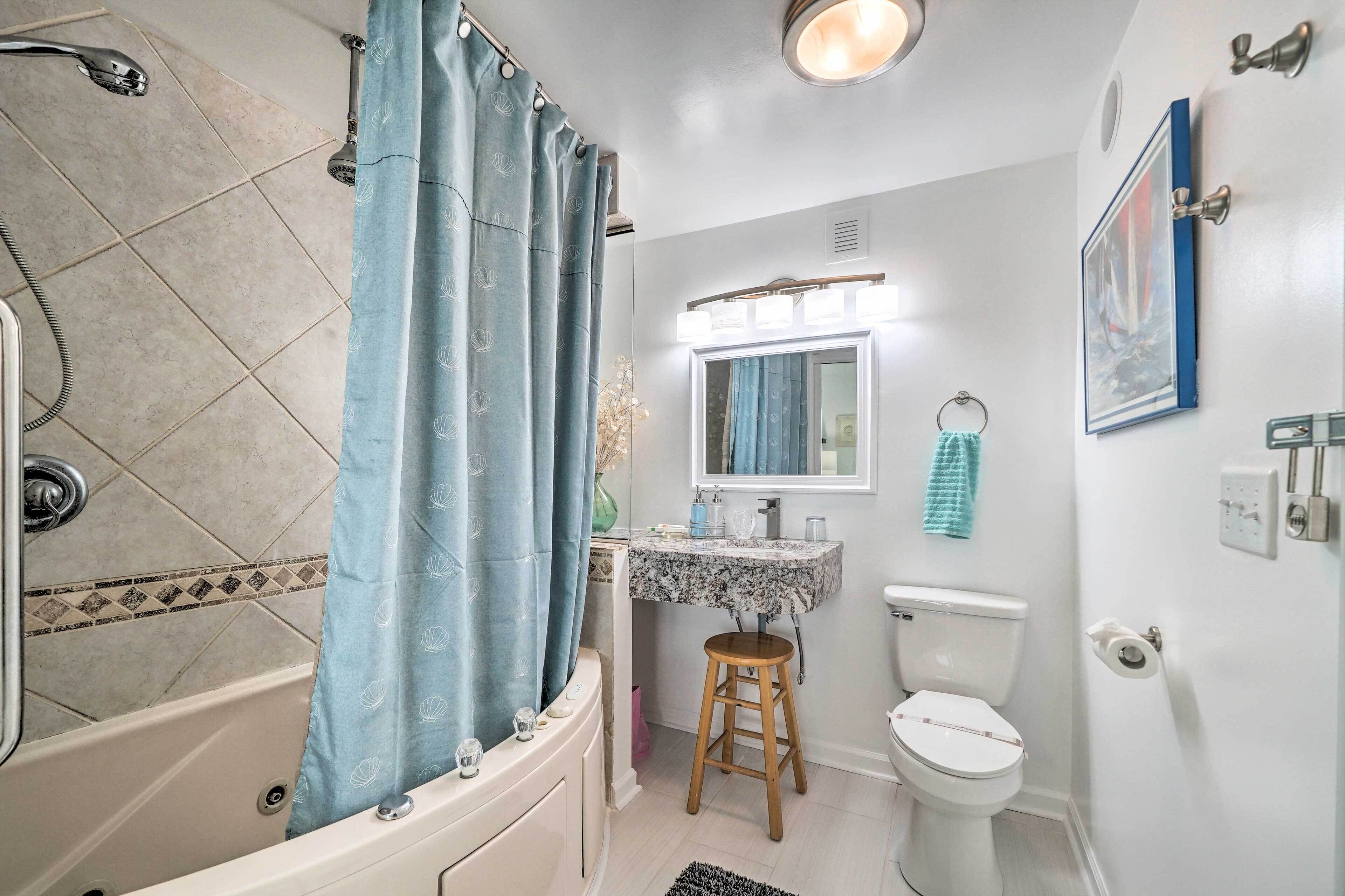 Un baño con bañera, inodoro, lavabo y un espejo sobre el lavabo.
