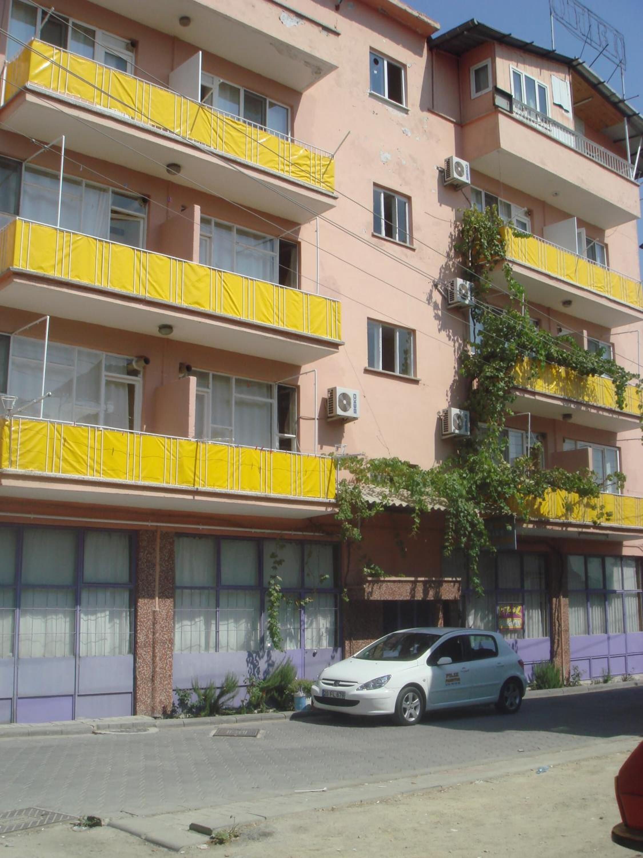 A multi-story building with balconies covered in yellow fabric.