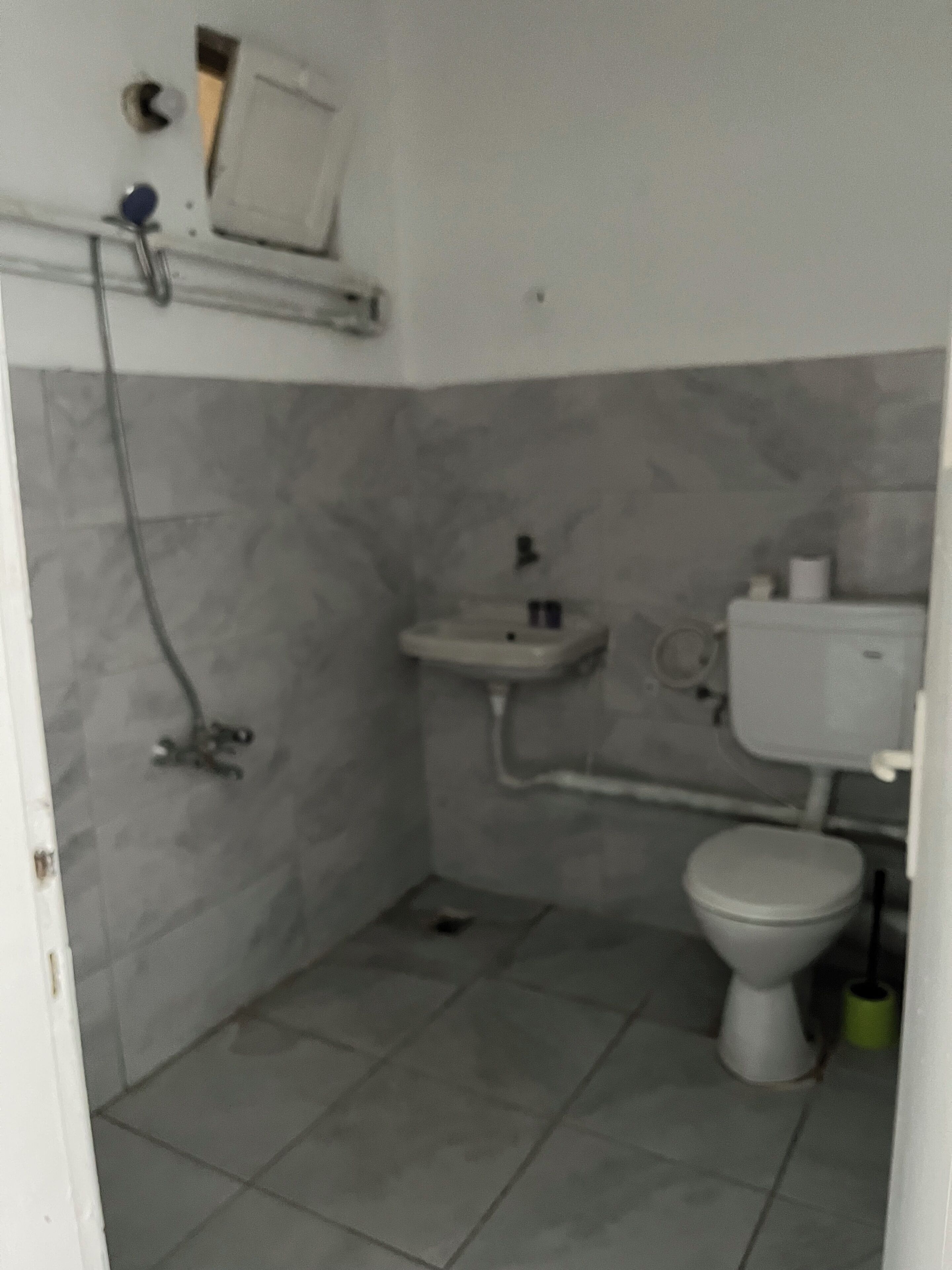 A small bathroom with a toilet, sink, and shower.