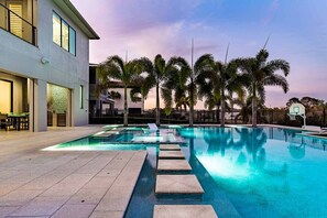 A swimming pool with a basketball hoop, palm trees, and a building with large windows. - Huge Estate Near Parks w/ Arcade, Game Loft, Theater, Themed BRs, Huge Spa Pool (Four Corners)