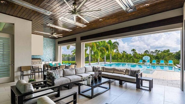 Ein großzügiger Innenbereich mit Blick auf einen Pool, moderne Möbel und ein Deckenventilator.