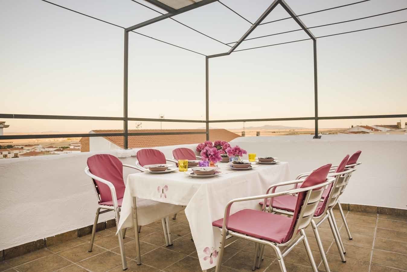A dining area with a table set for four, surrounded by chairs, overlooking a desert landscape.