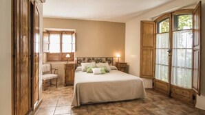 Ein Schlafzimmer mit Bett, Sessel, Nachttisch, Fenster und Kleiderschrank.