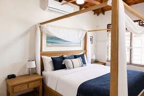 Un lit à baldaquin, une table de chevet avec une lampe et un tableau encadré au mur.