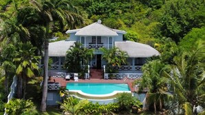 Une grande maison avec une piscine, entourée d’une végétation luxuriante.