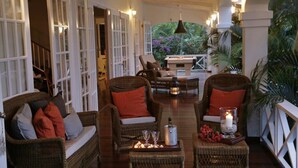 Un salon confortable, doté de meubles en osier, d’une cheminée et offrant une vue sur une végétation luxuriante.
