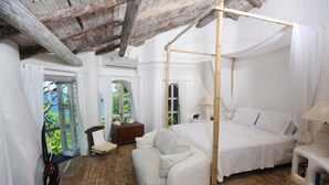 A bedroom with a four-poster bed, a sofa, and a wooden floor. - Smuggler's Nest - Exotic & romantic villa 2 bedroom Tropical Retreat (Cap Estate)