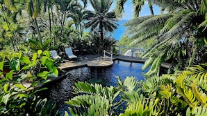 A tropical resort with a swimming pool surrounded by lush greenery and palm trees. - Smuggler's Nest - Exotic & romantic villa 2 bedroom Tropical Retreat (Cap Estate)