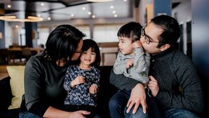 A family sitting on a couch in a modern interior with circular ceiling lights.