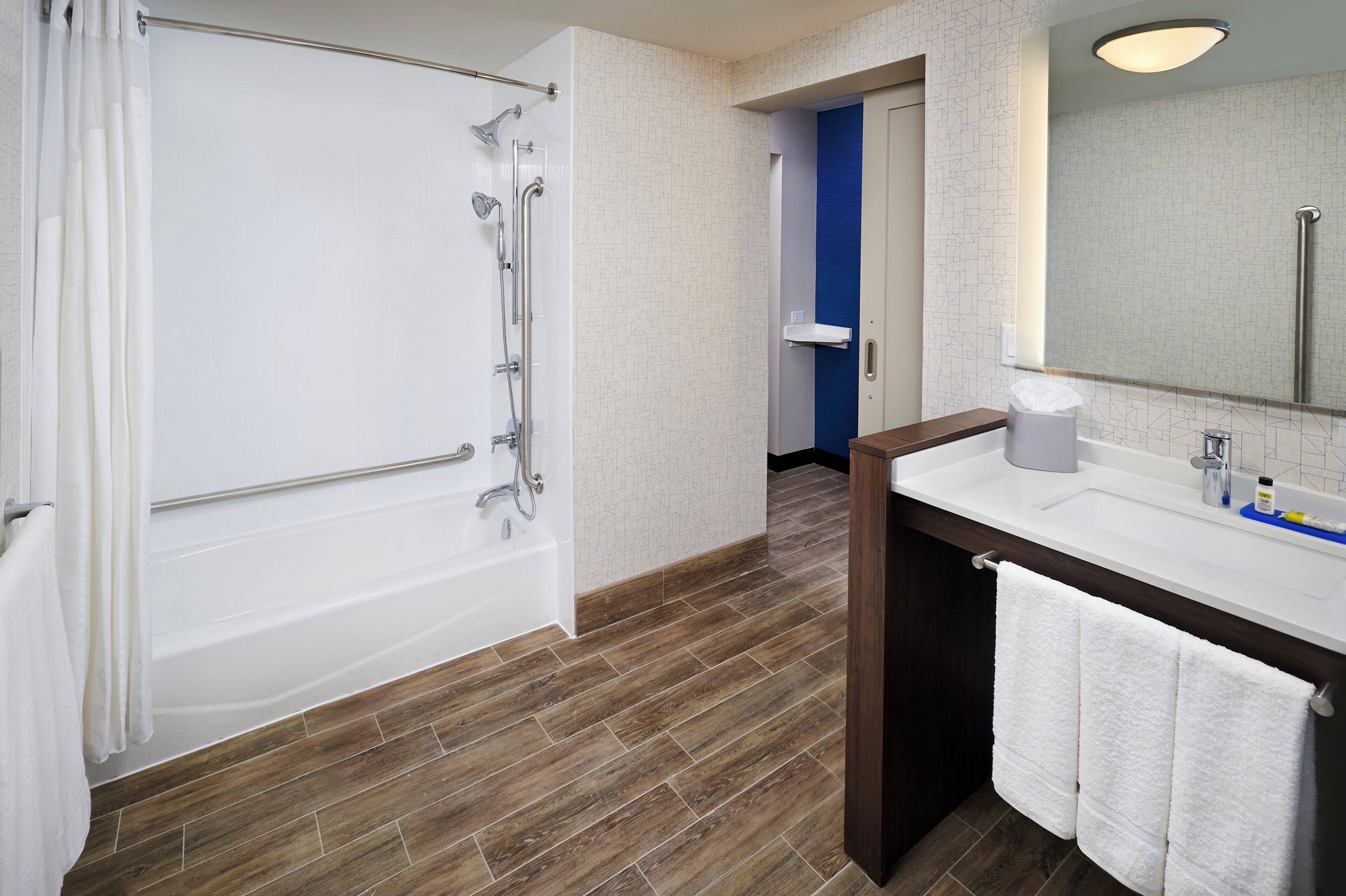 Un baño con bañera, lavamanos, espejo y ducha.