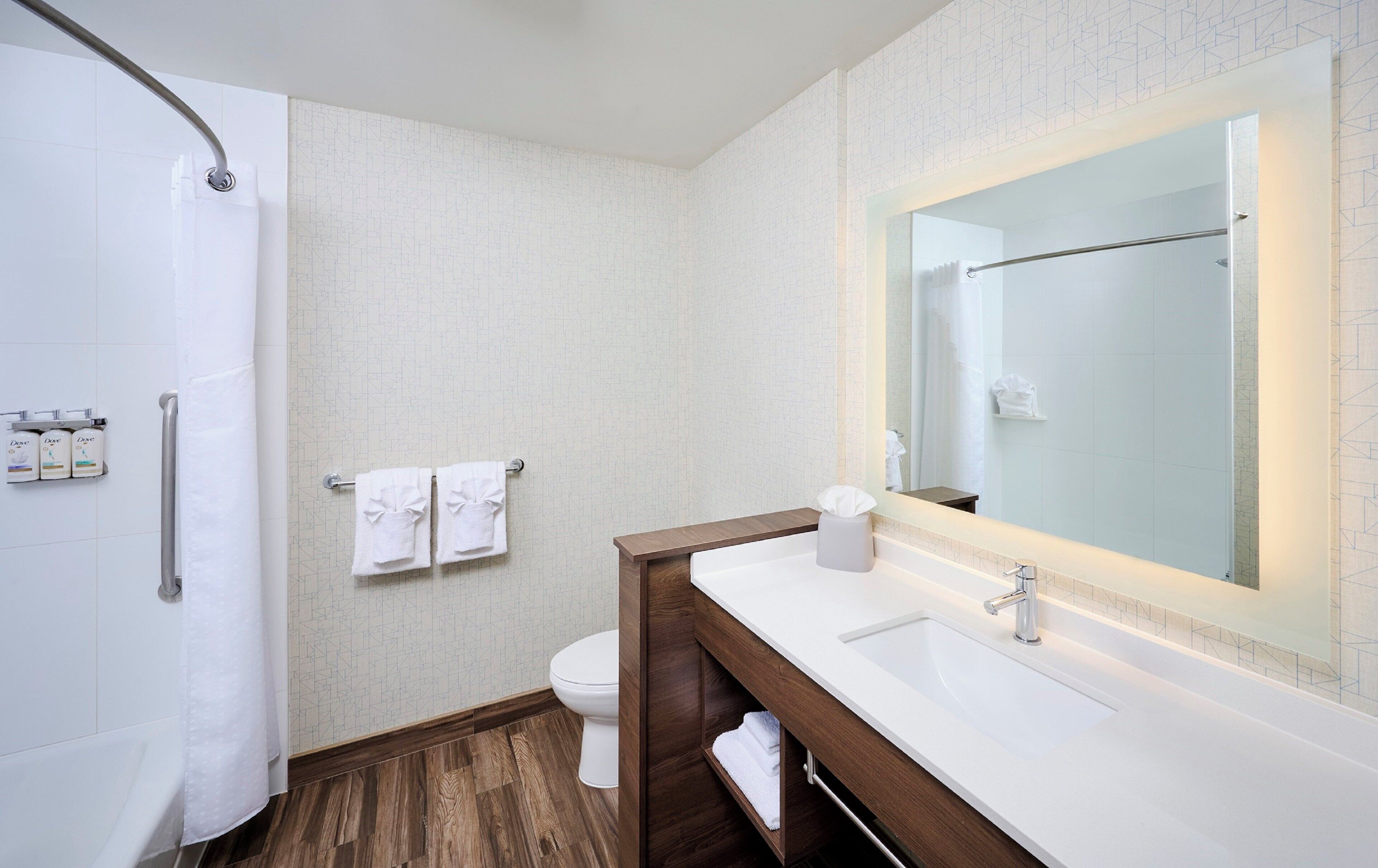 A modern bathroom with a shower, toilet, and vanity.