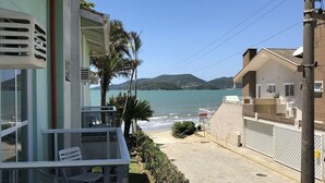 Un balcón con sillas blancas, vista a la playa y un edificio con balcón.