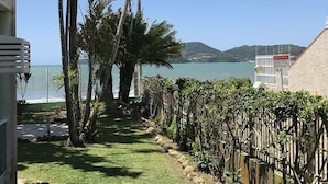 Una propiedad costera con vista al mar, un jardín cercado con palmeras y un edificio con un letrero.