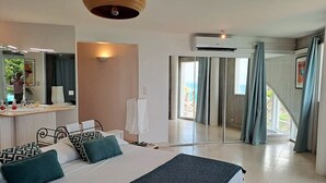 Une chambre moderne avec un grand lit, une table de chevet, un miroir et une vue sur l’extérieur grâce à une porte-fenêtre coulissante.