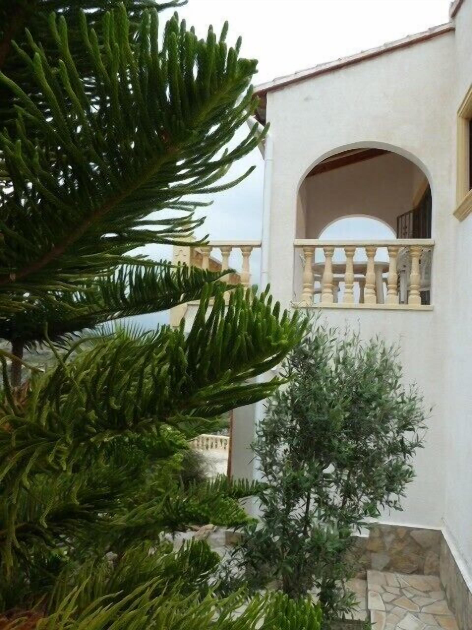 A courtyard with a white building featuring an arched window and a balcony.