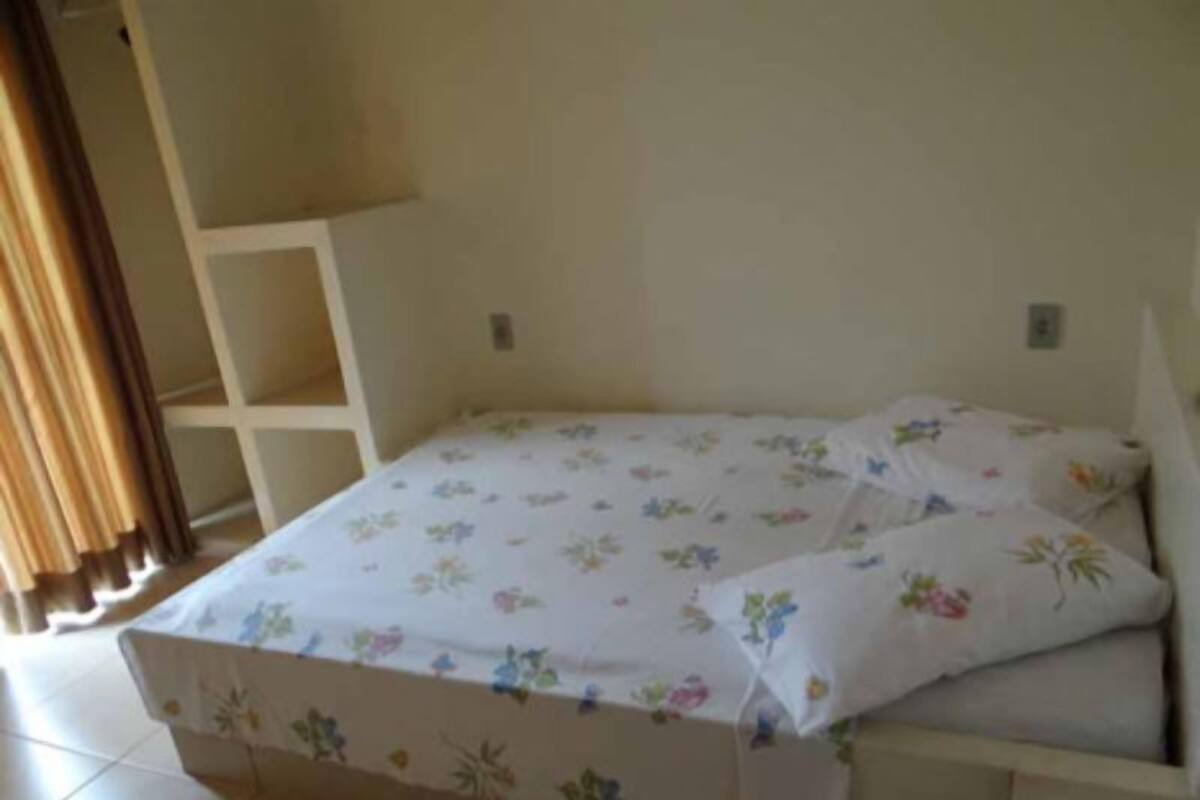 Una habitación pequeña con una cama individual, una colcha de motivos florales y almohadas a juego.
