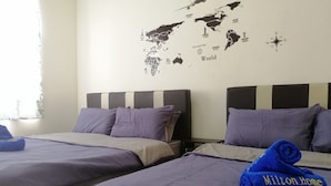 A hotel room with two beds, each with a headboard and pillows. There is a world map on the wall and a rolled towel on one bed. - Sentul Village Milton Home by Enjoy (Kuala Lumpur)