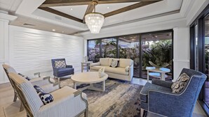 A modern living room with a chandelier, sofas, and a coffee table. - Modern 11th Floor Beachfront Condo With Views/pool (Marco Island)